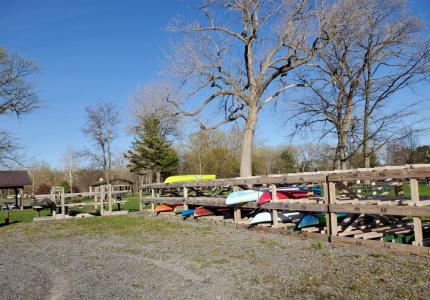 wooden kayak storage rack with different colored kayaks on sunny day early spring