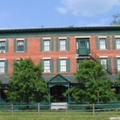 Red brick building, green paneling, blue skies, two small trees in front