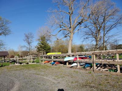 wooden kayak storage rack with different colored kayaks on sunny day early spring